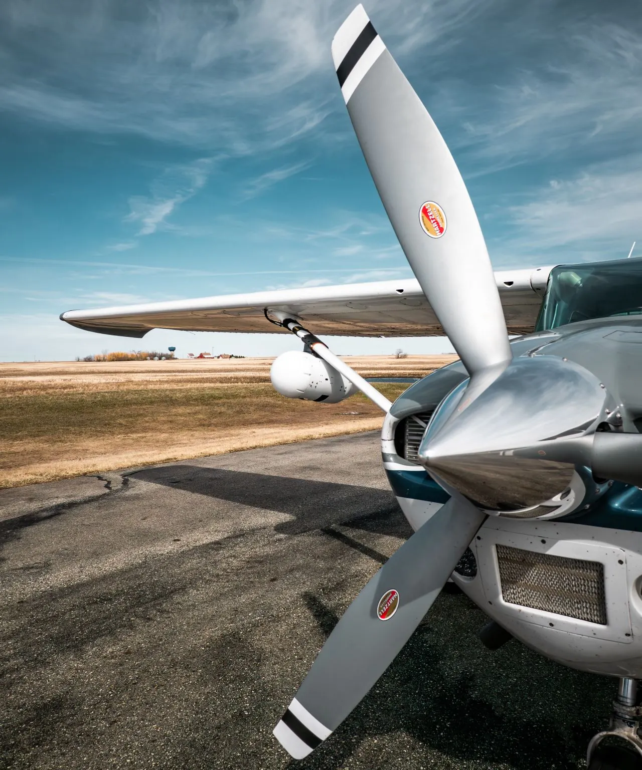 Fixed wing aircraft on a prairie airstrip with a gyro-stabilized sensor pod mounted under the wing